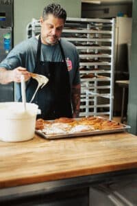 David Escobar, owner of Papi's Ohana, putting frosting on cinnamon rolls.