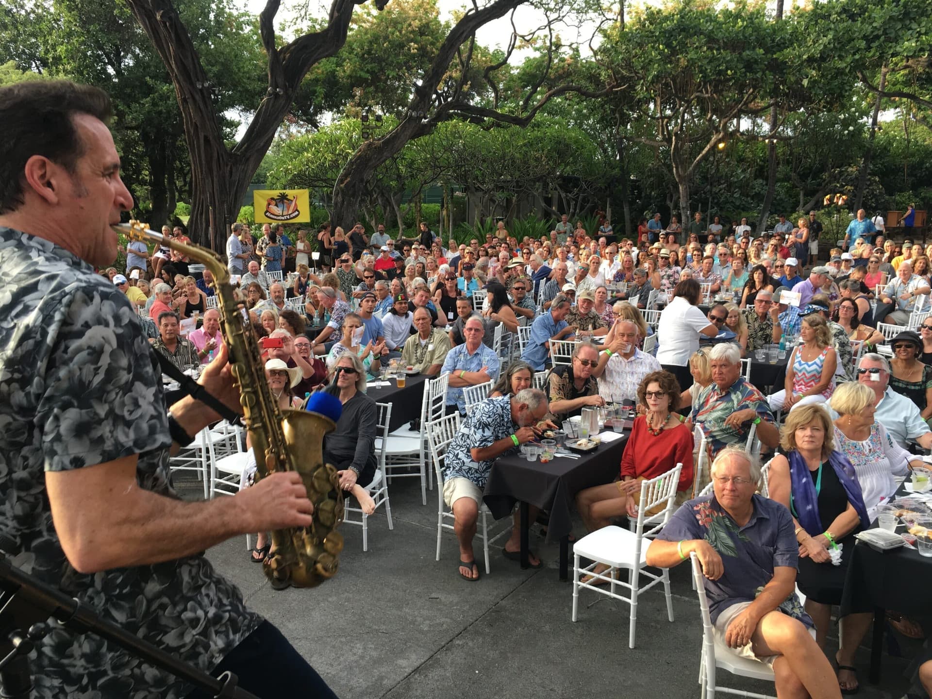 Man performing saxophone in front of a crowd at a concert on Big island Hawaii.