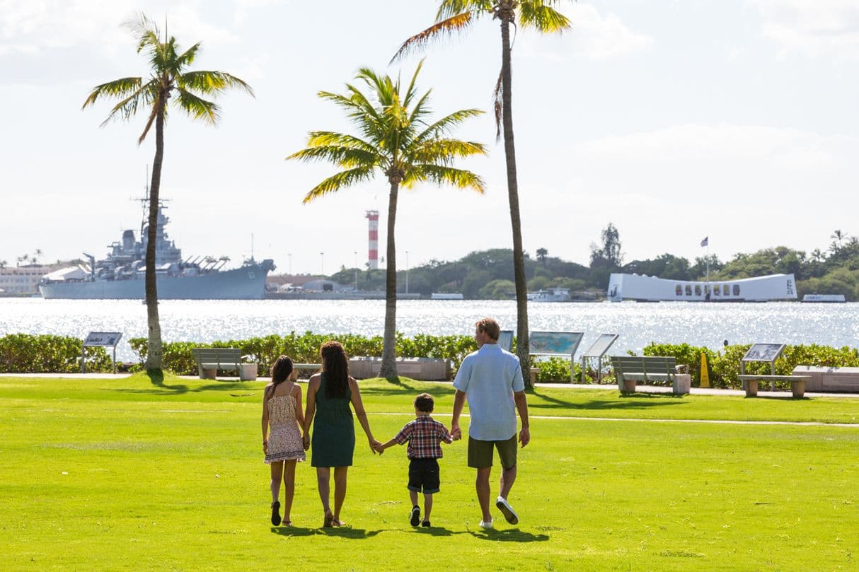 A family walking through grass at Pearl Harbor, Honolulu Hawaii.