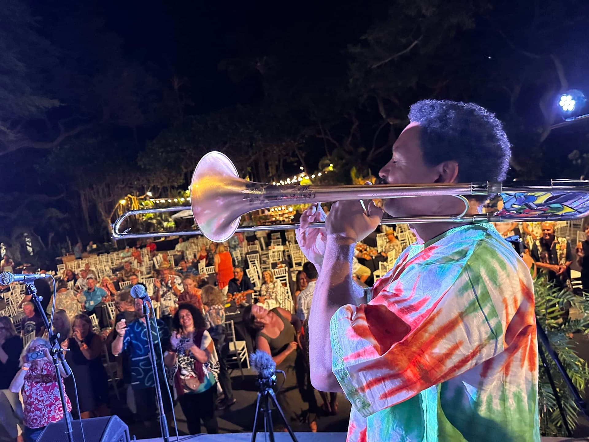 jazz musician playing trumpet in front of crowd at concert at night