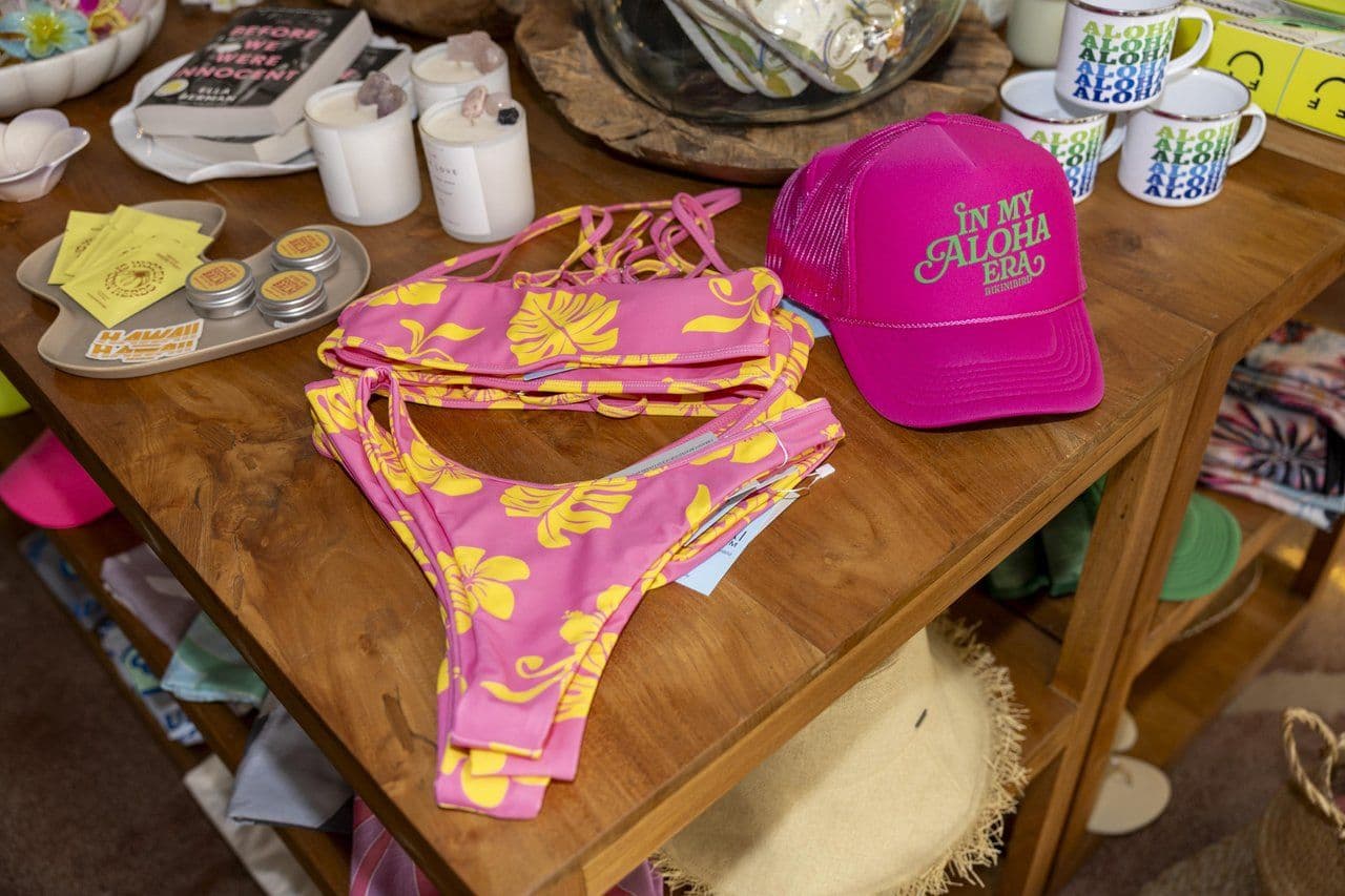 A bikini, trucker hat and coffee mugs in a retail shop.