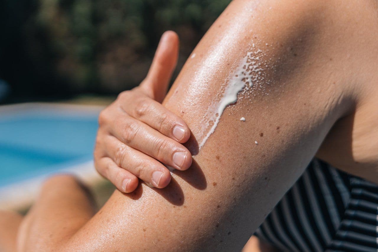 Woman slathering on sunscreen at the beach.