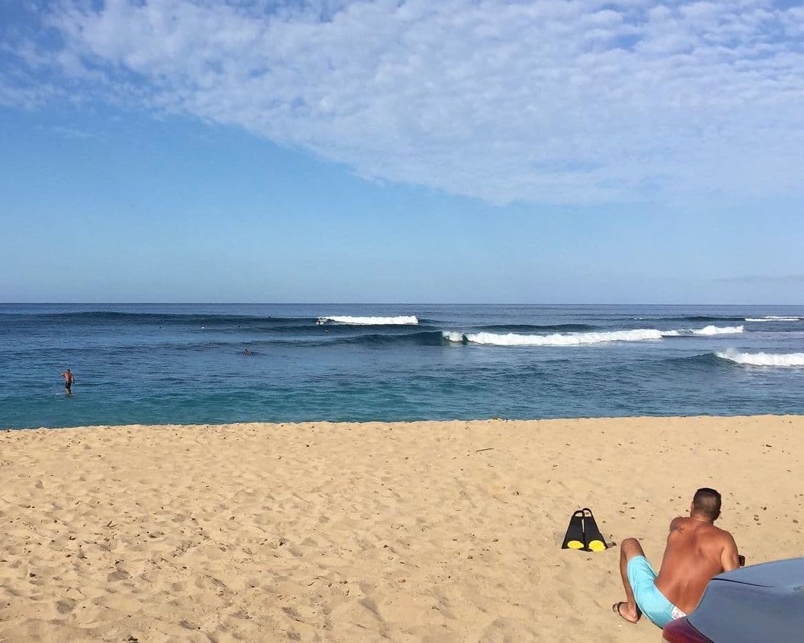Man sitting on beach with flippers in hawaii.
