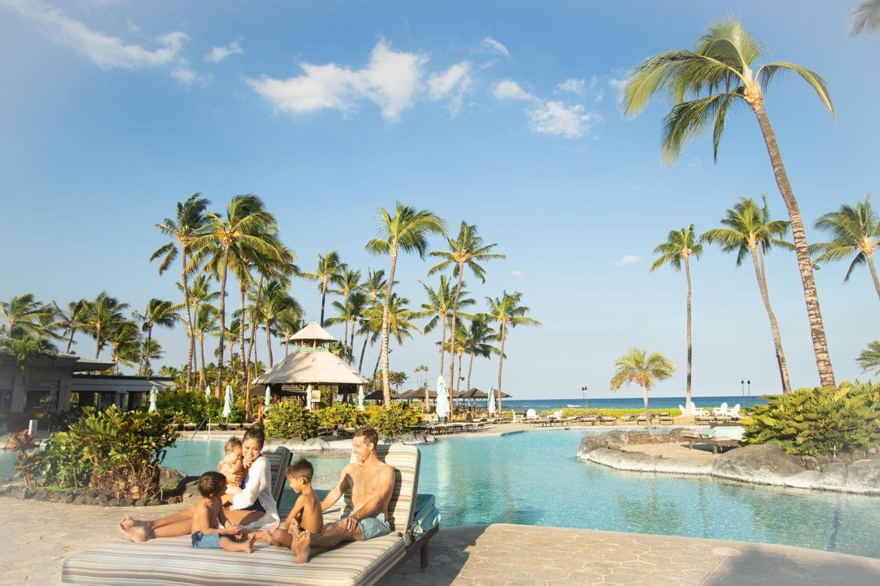 Family sitting by the pool in hawaii.