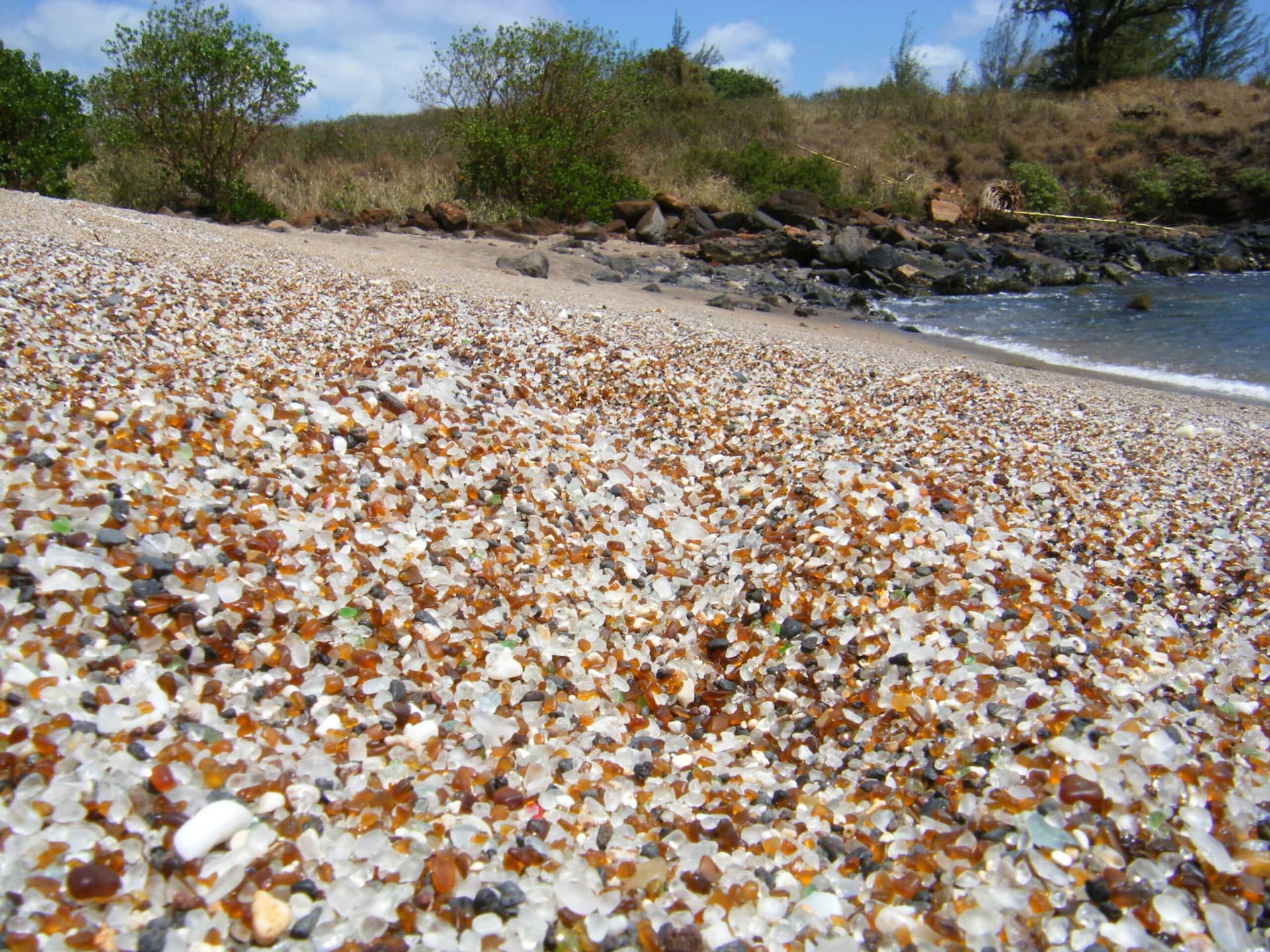 Sea glass mixed with sand on a beach.
