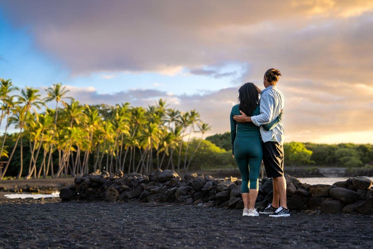 A couple gazing at the sunset on lava fields in Hawaii.