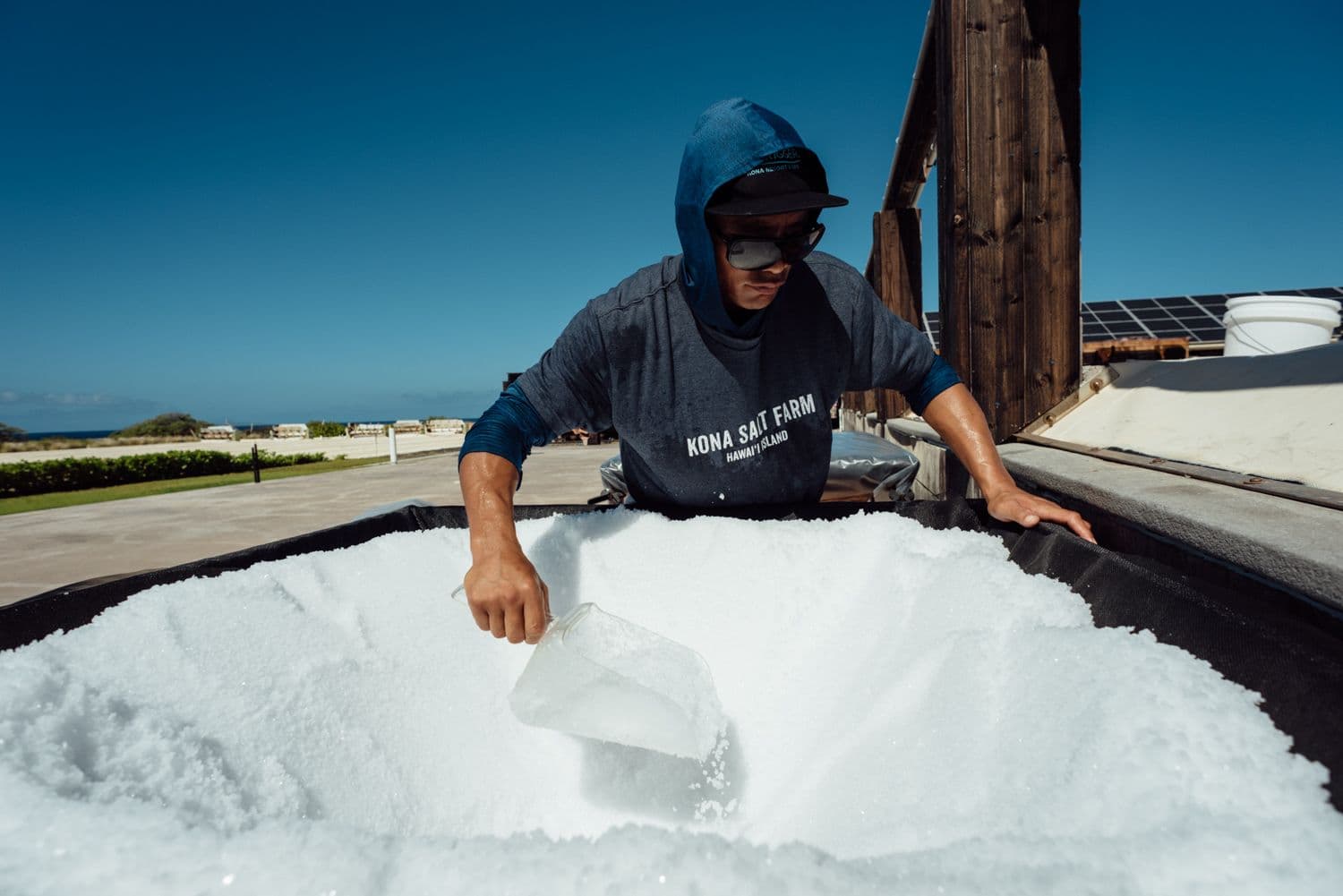 man scooping sea salt from huge mound