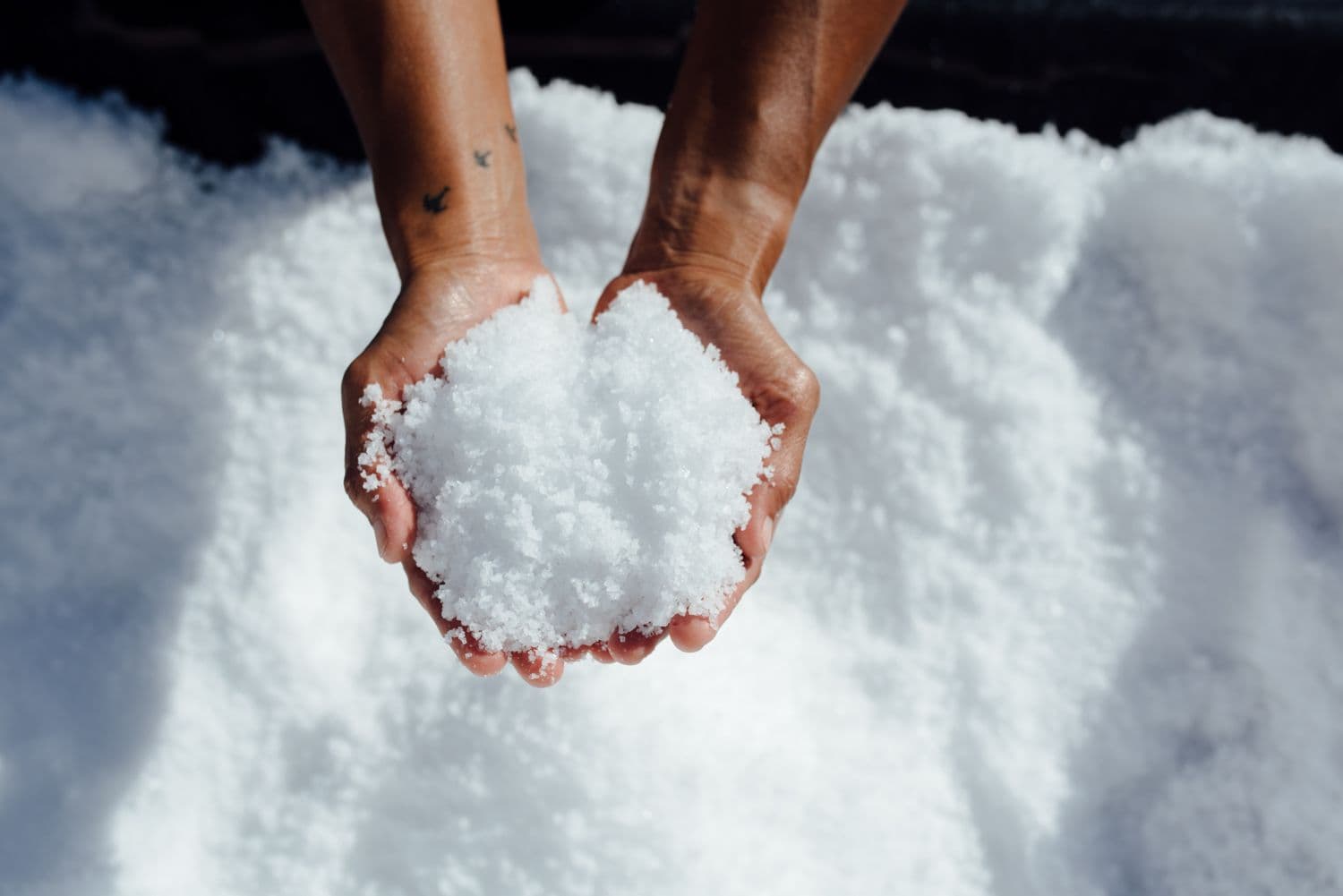 Two hands holding a pile of sea salt.