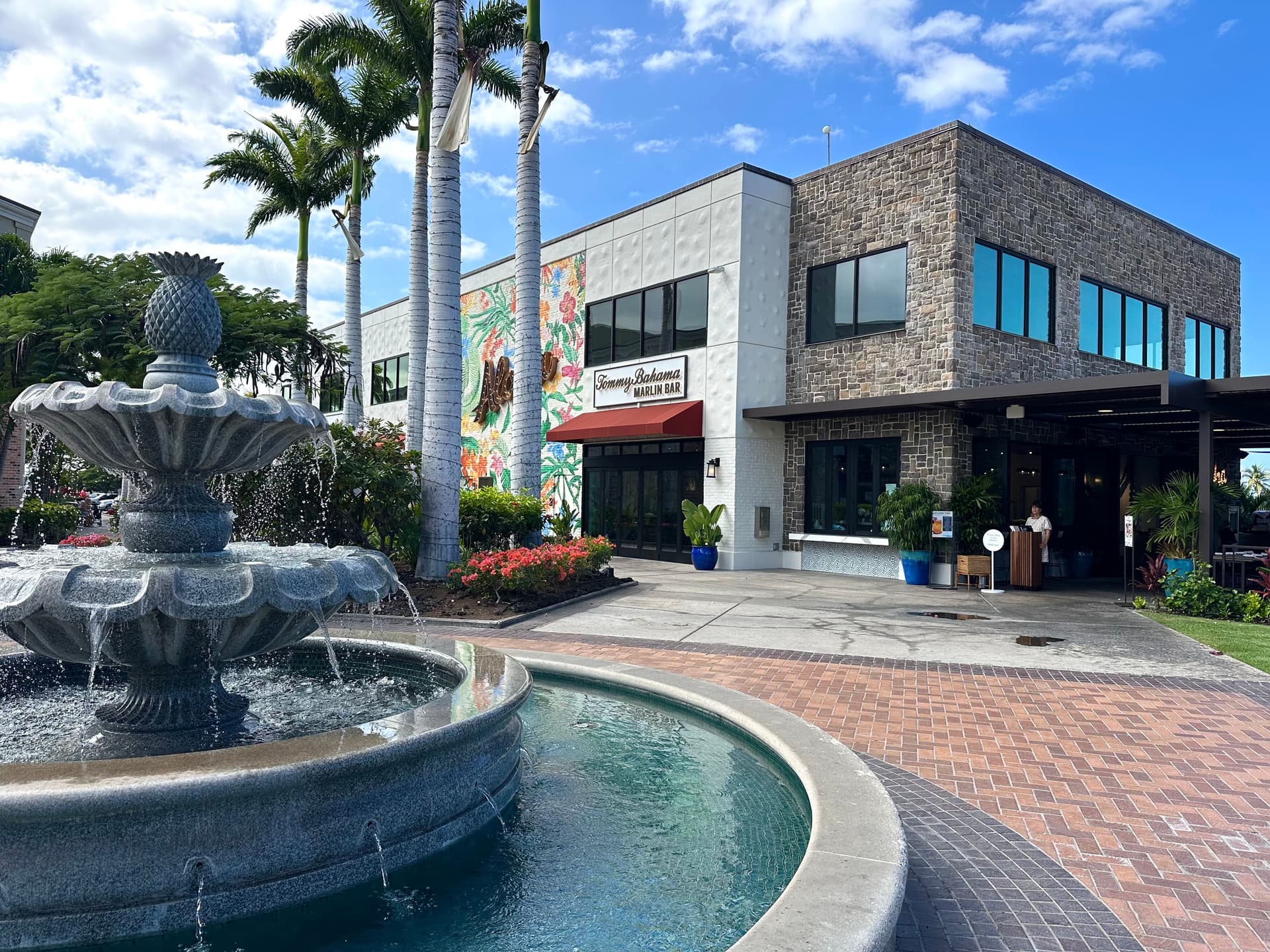 Outdoor shopping center with fountain and restaurant.