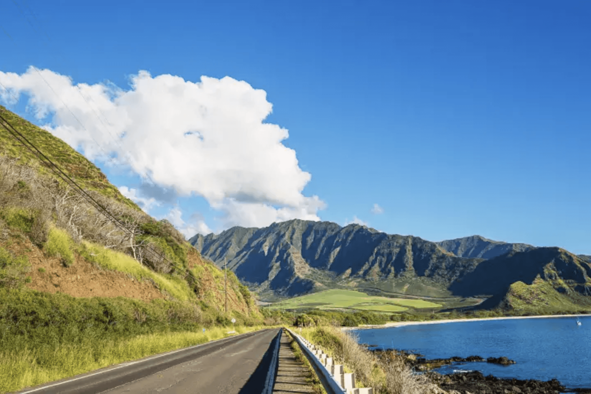 road with mountains and ocean in background