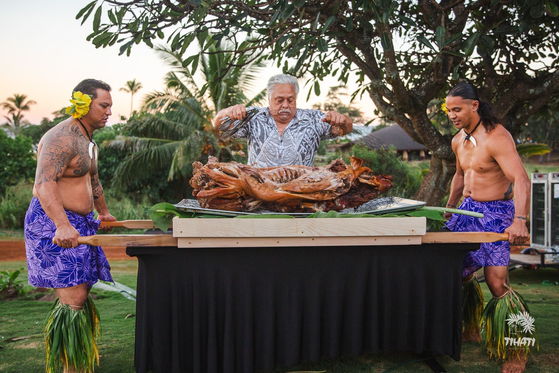 men preparing a whole roast pig for luʻau