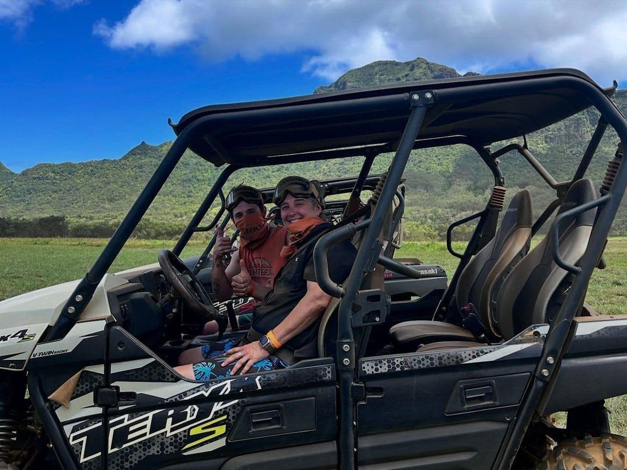 two people in an ATV in front of green mountains on Kauai